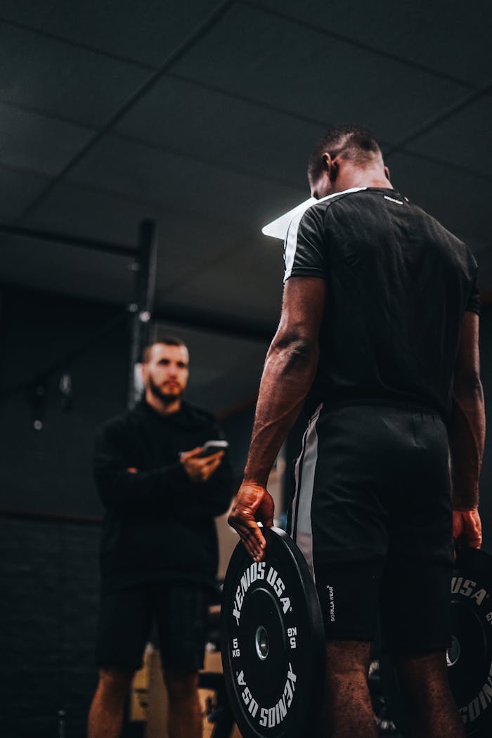 Focused strength training with a personal trainer in a gym setting.